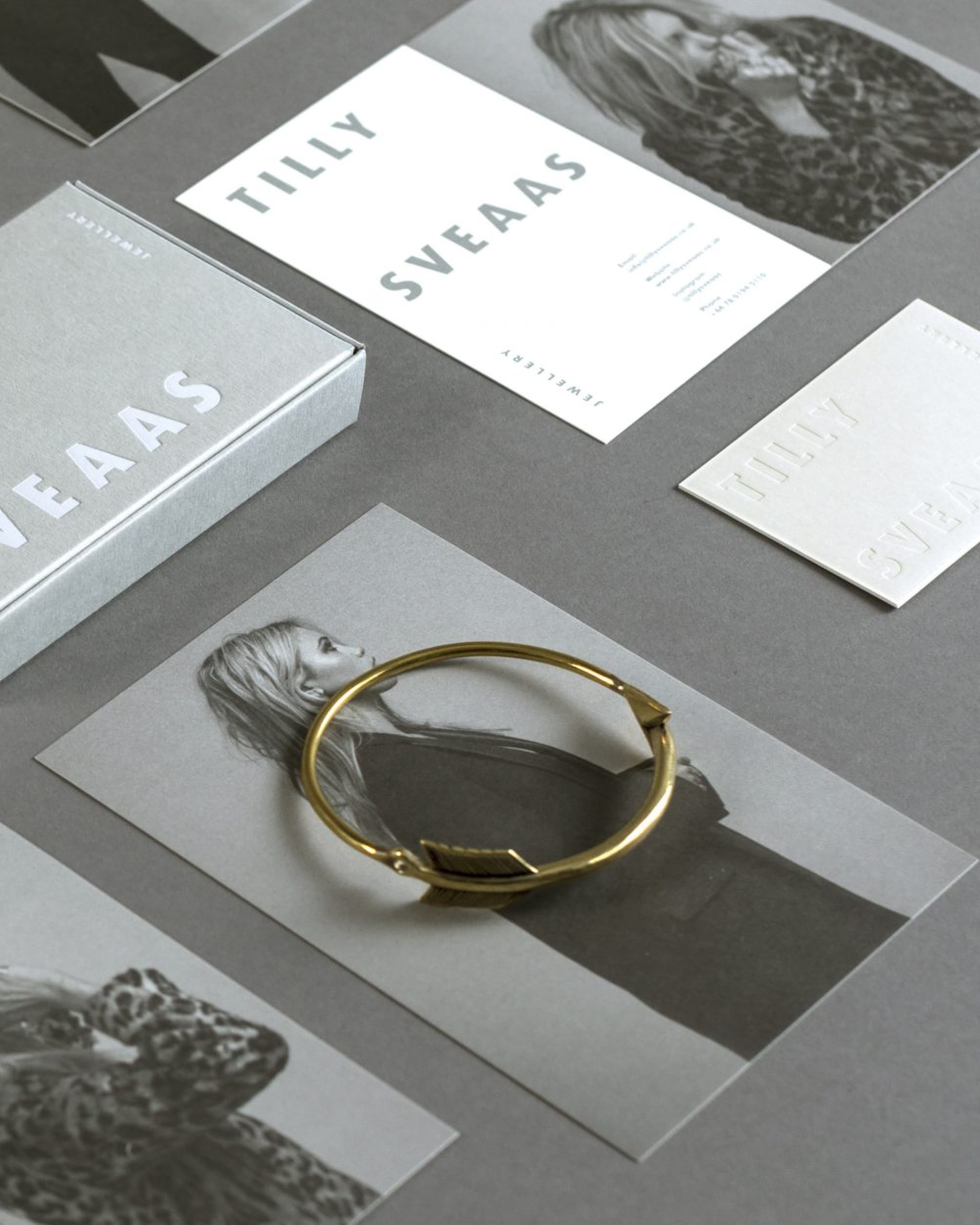 Tilly Sveaas Jewellery brand identity flatlay showing a gold bangle bracelet on a portrait print, alongside branded stationery including business cards, a letterhead, and a gray gift box.