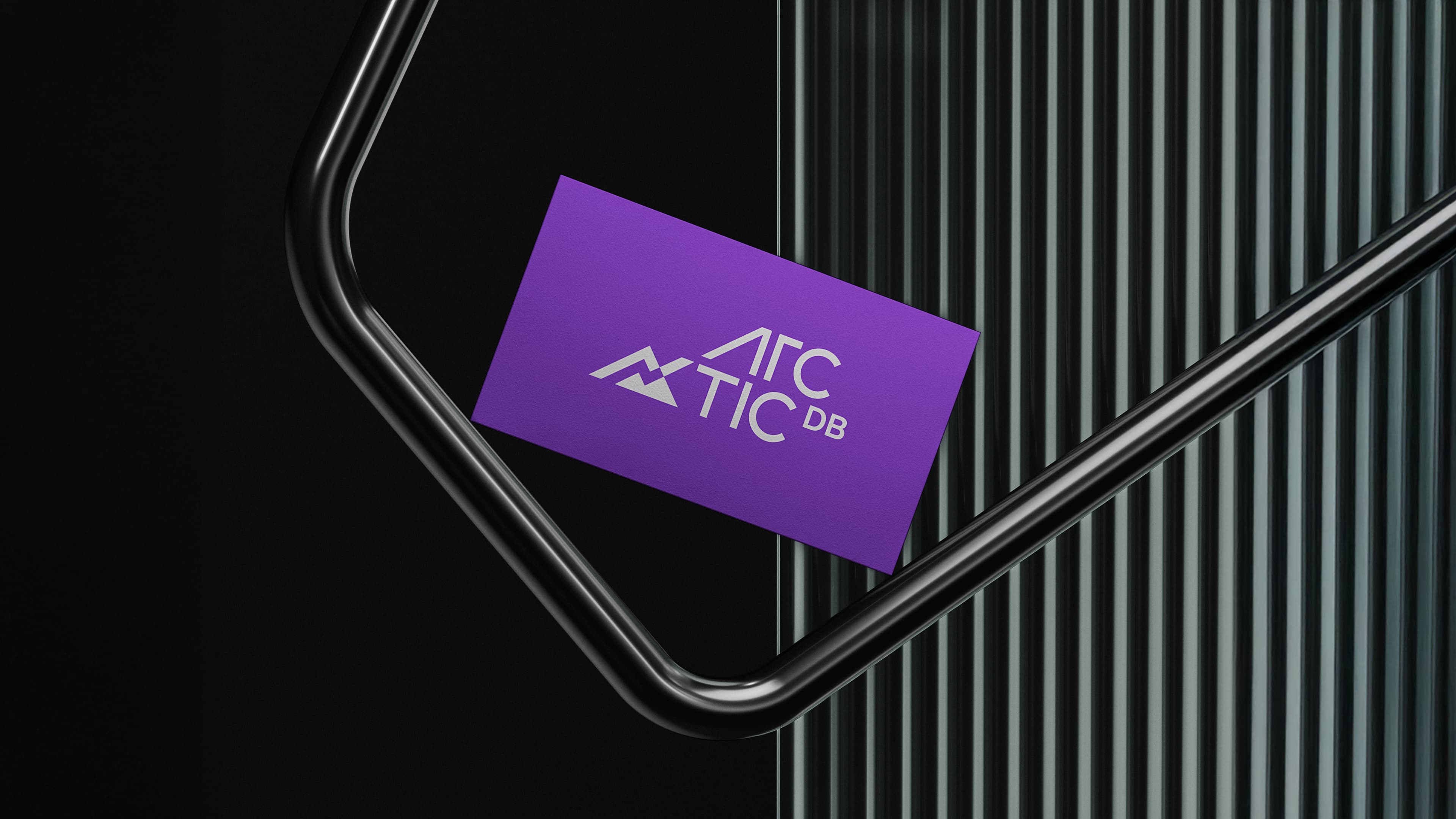 "A purple business card featuring the Arctic DB logo — a stylized mountain and graph icon with 'ARC TIC DB' text — resting on black curved railings against a ribbed metal background."